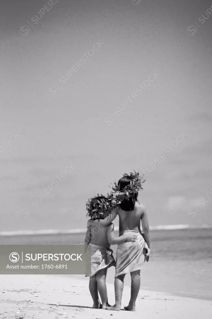 Little Polynesian sisters in haku and pareo on beach, View from behind Black and white photograph 