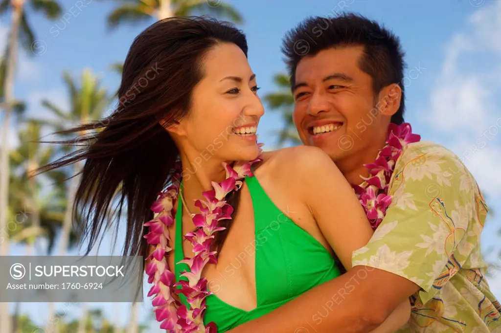 Japanese couple on the beach wearing leis 