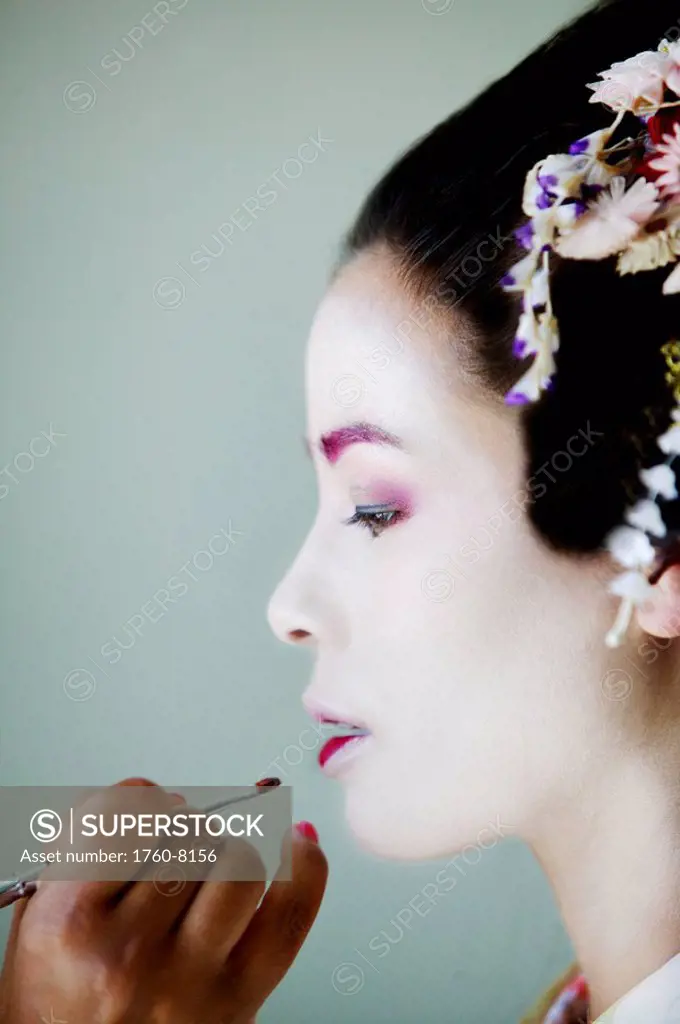 Young maiko having her traditional lipstick applied.