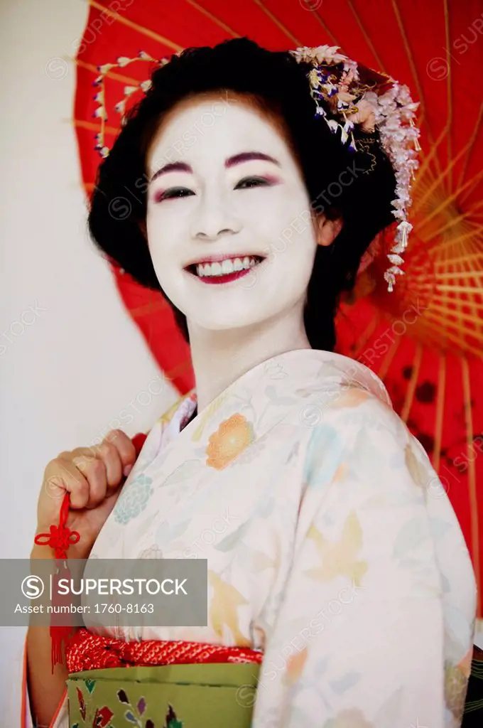 Portrait of a Maiko holding umbrella smiling.