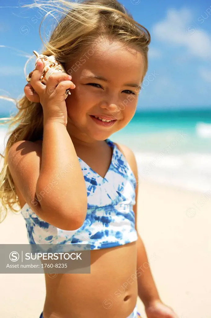Hawaii, Oahu, Adorable little girl holding seashell along the waters edge.