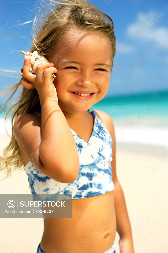 Hawaii, Oahu, Adorable little girl holding seashell along the waters edge.