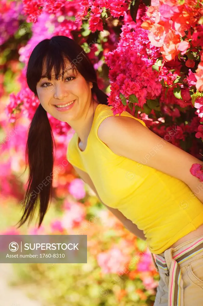 Young Japanese girl posing with bright pink flowers.
