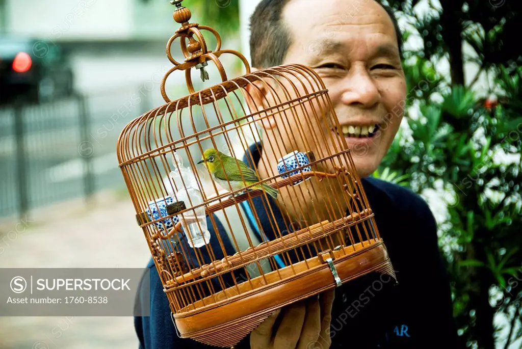 Hong Kong, Mong Kok K, A birder attends to his bird at the Yuen Po Street Bird Garden.