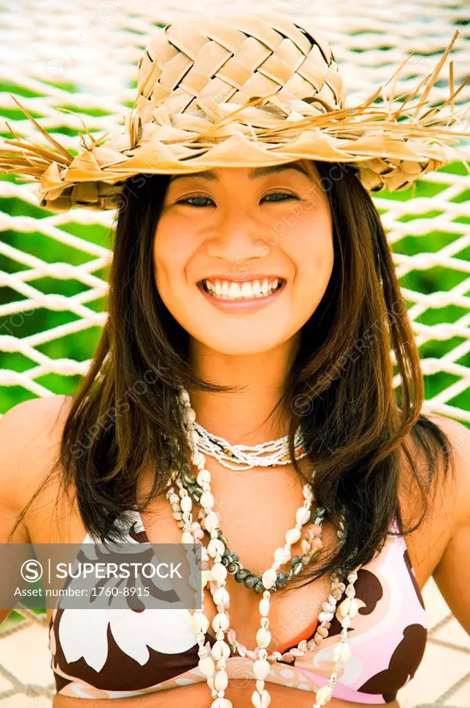 Hawaii, Oahu, Lanikai, Japanese woman in hammock with straw hat.