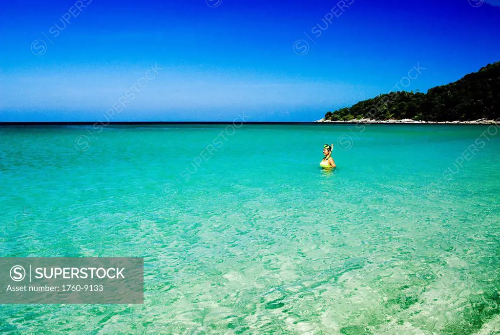 Thailand, Phuket, Karon Beach, Woman with mask and snorkel in bright clear tropical water.