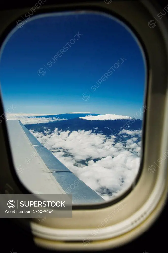 Hawaii, Big Island, Aerial view of Mauna Kea and Mauna Loa covered in snow through an airplane window.