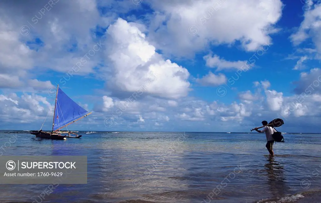 Hawaii, Kauai, Hanalei Bay, Man with paddle wading out into water to sailing canoe.