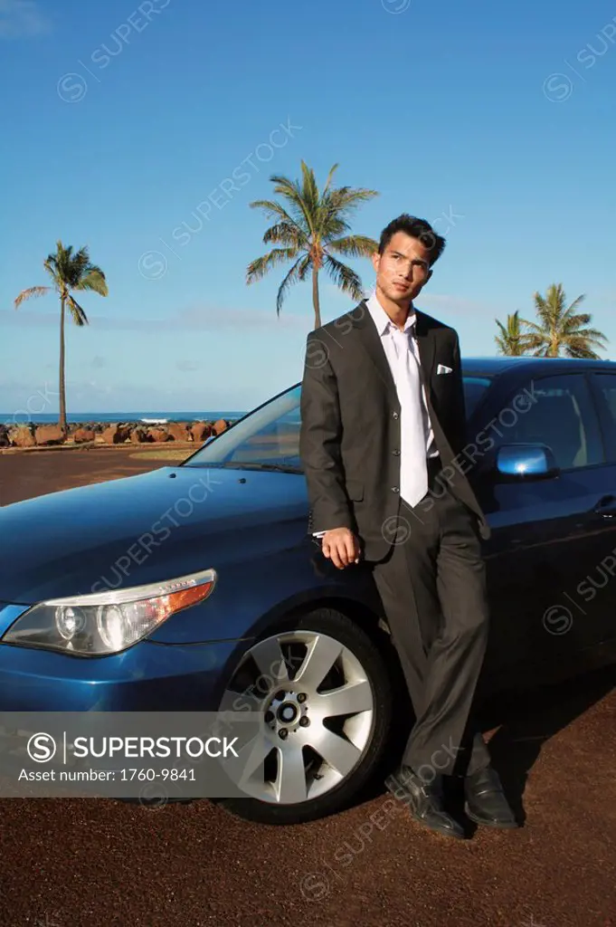 Hawaii, Oahu, Business man in his suit next to a luxury car.