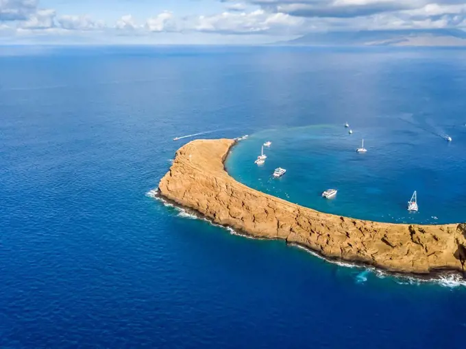 Molokini Crater, aerial shot looking at the backwall of the crescent shaped islet at mid-morning with charter boats inside; Maui, Hawaii, United State...