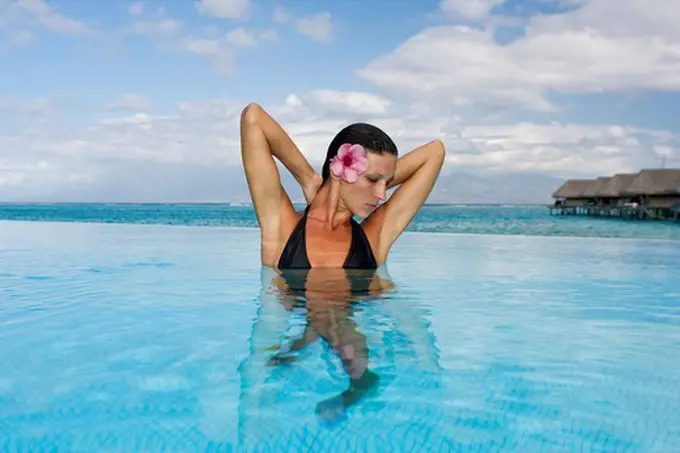French Polynesia, Moorea, Woman relaxing in oceanside resort pool.