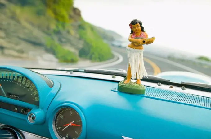 Plastic hula doll on the dashboard of a turquoise Thunderbird.