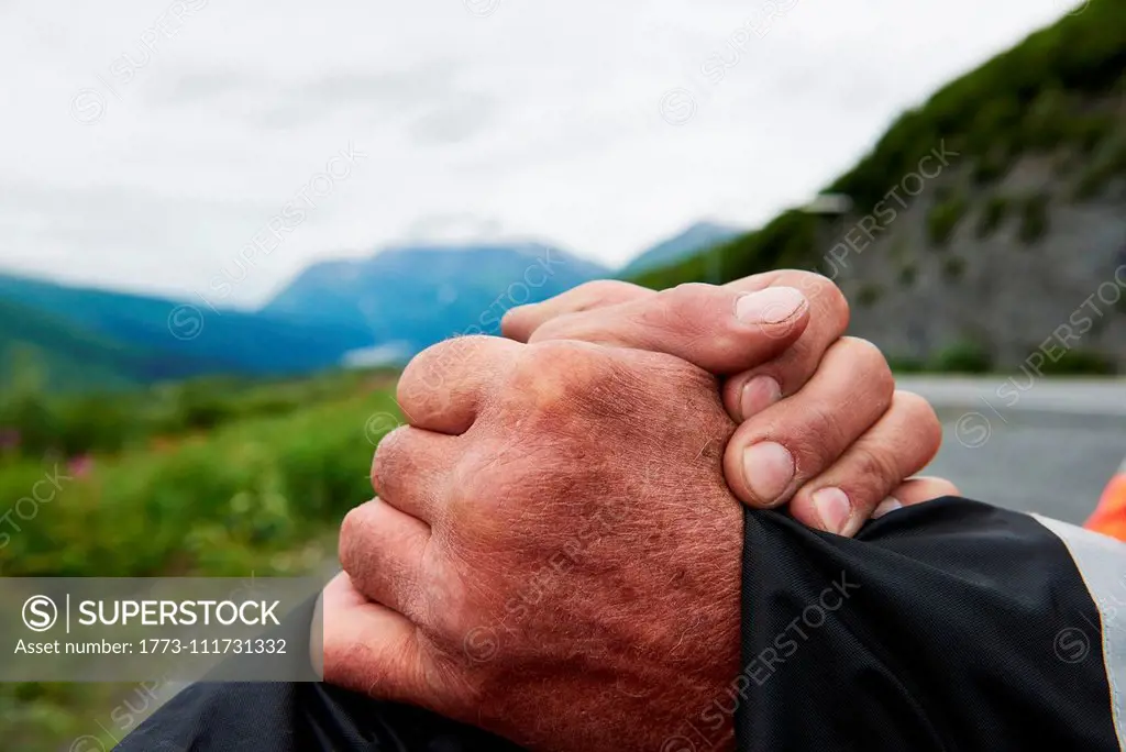 Senior man and son shaking hands in mountain landscape, close up, Valdez, Alaska, USA