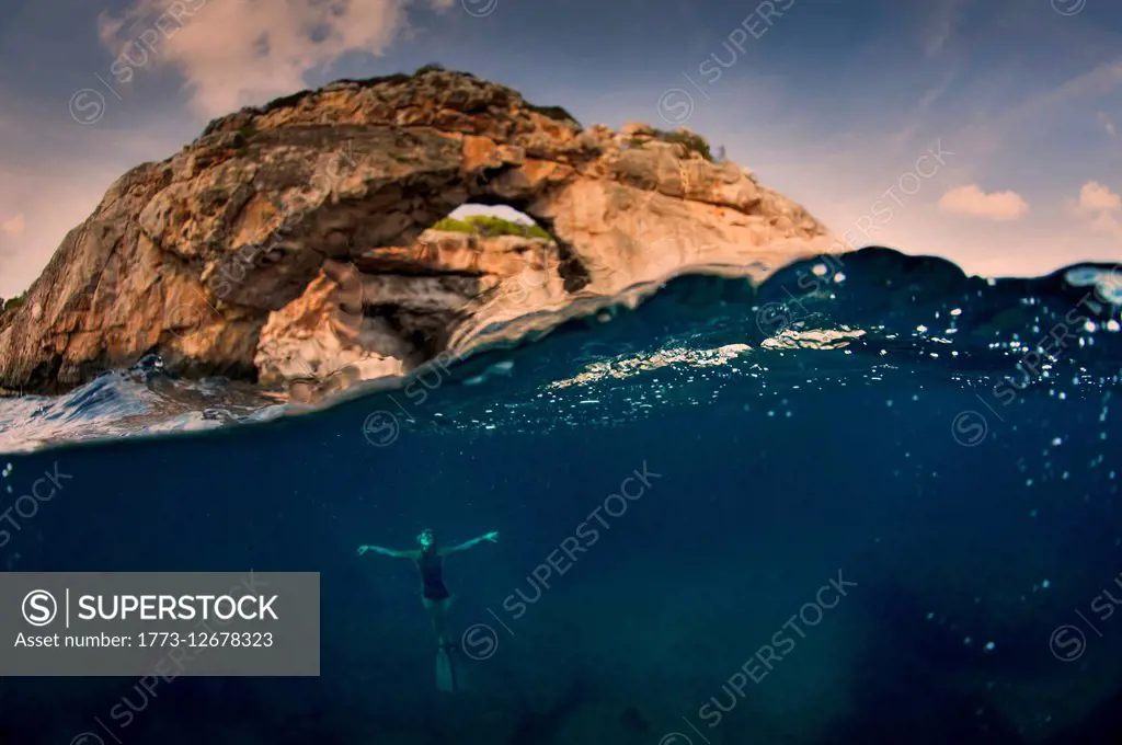 Woman underwater with arch, Santany, Mallorca, Spain