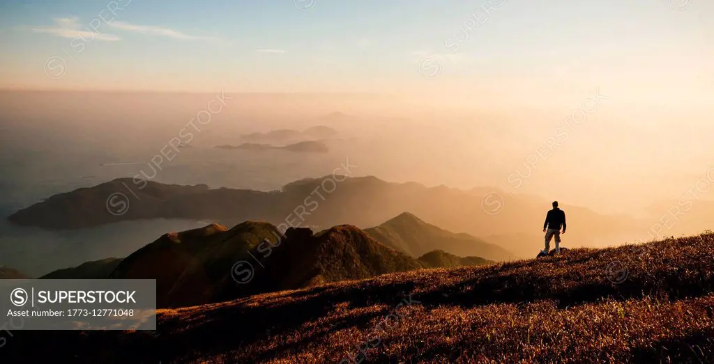 Rear view of hiker hiking on Lantau Peak, Lantau Island, Hong Kong, China