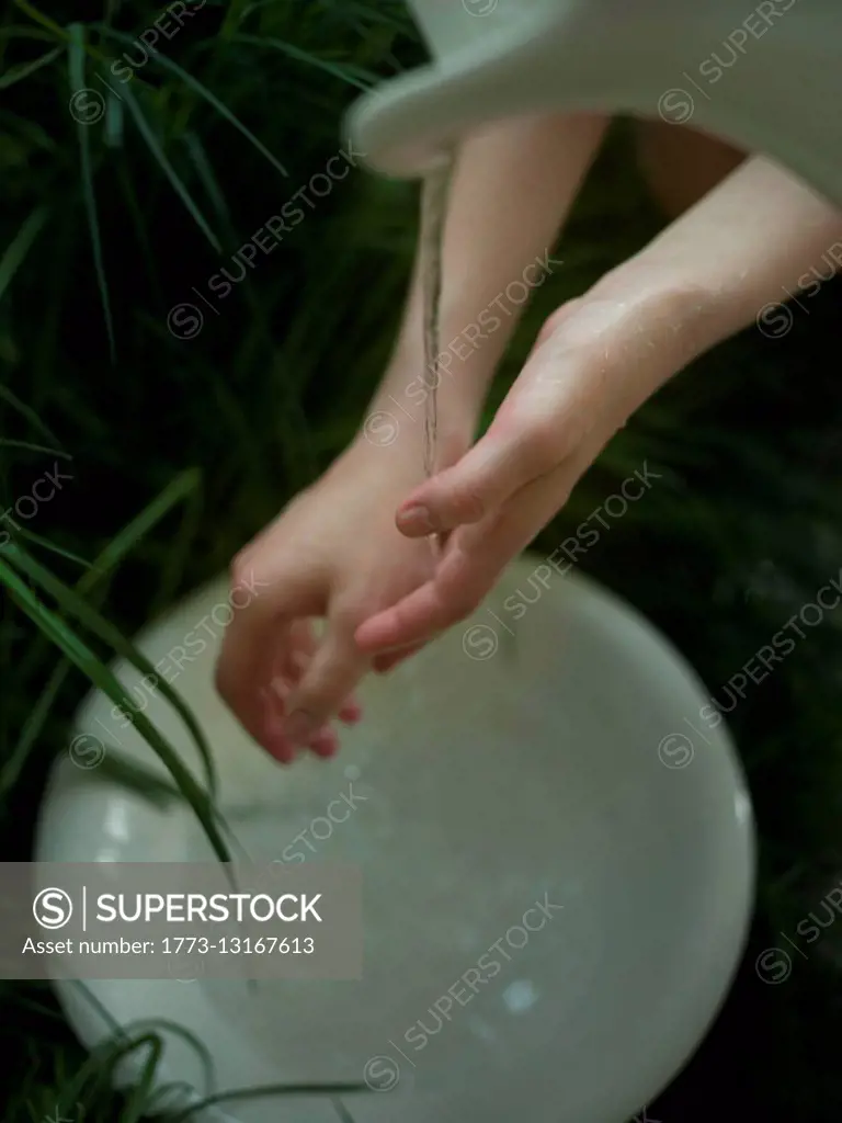 Young woman washing hands under flowing water, close-up