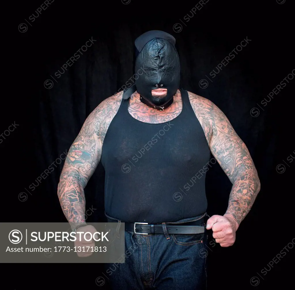 Front view of mature tattooed man wearing vest and face mask
