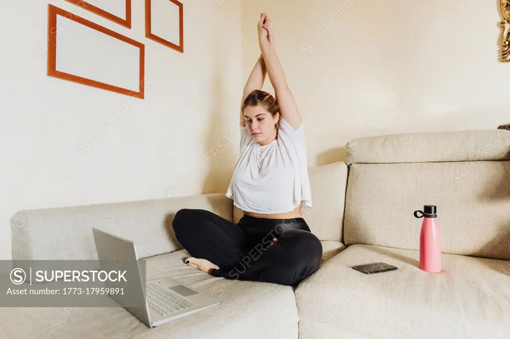 Young woman stretching, taking online exercise class