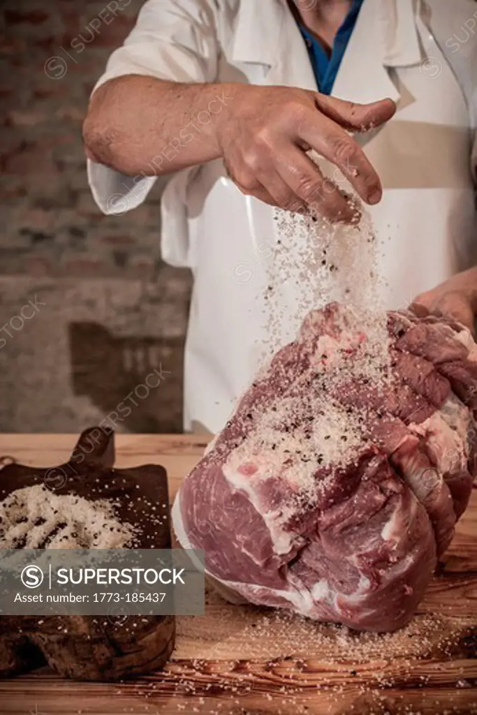 Butcher spicing meat in shop