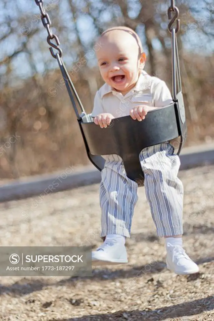 Baby boy playing on swing in park