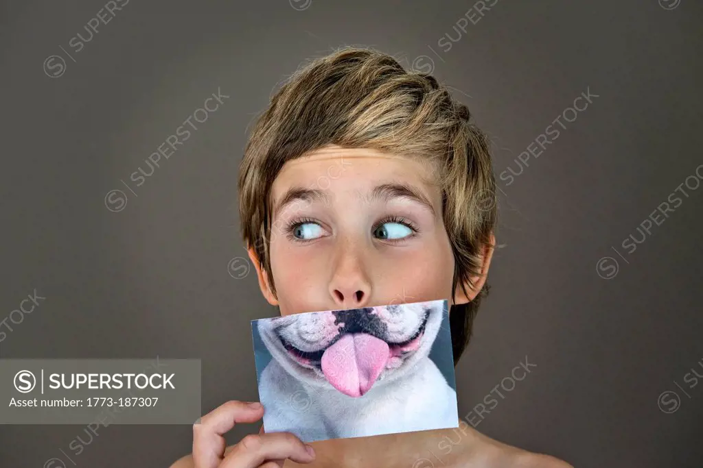 Boy holding picture of dog over face
