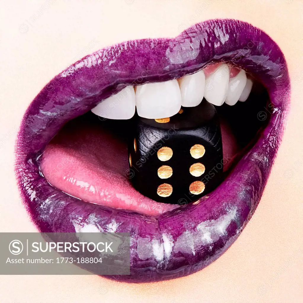 Woman in lip gloss with dice in mouth