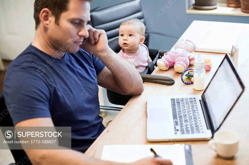 Baby girl sitting with father at work