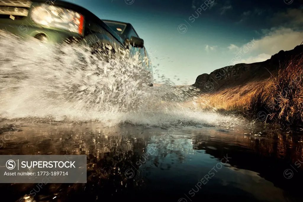 Car splashing in still rural puddle