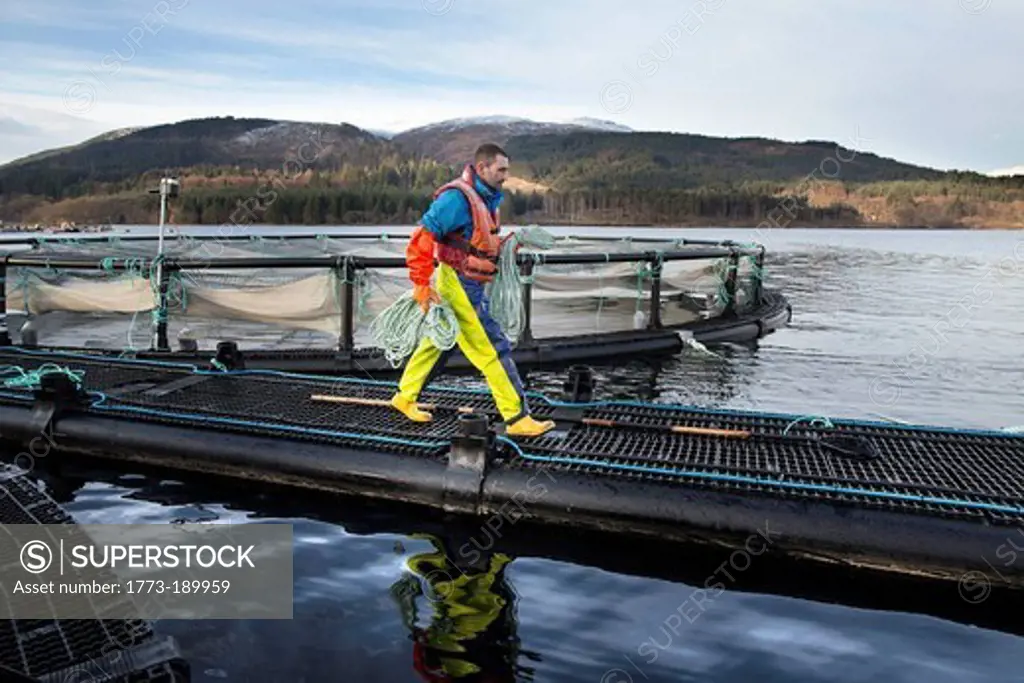 Worker on salmon farm in rural lake