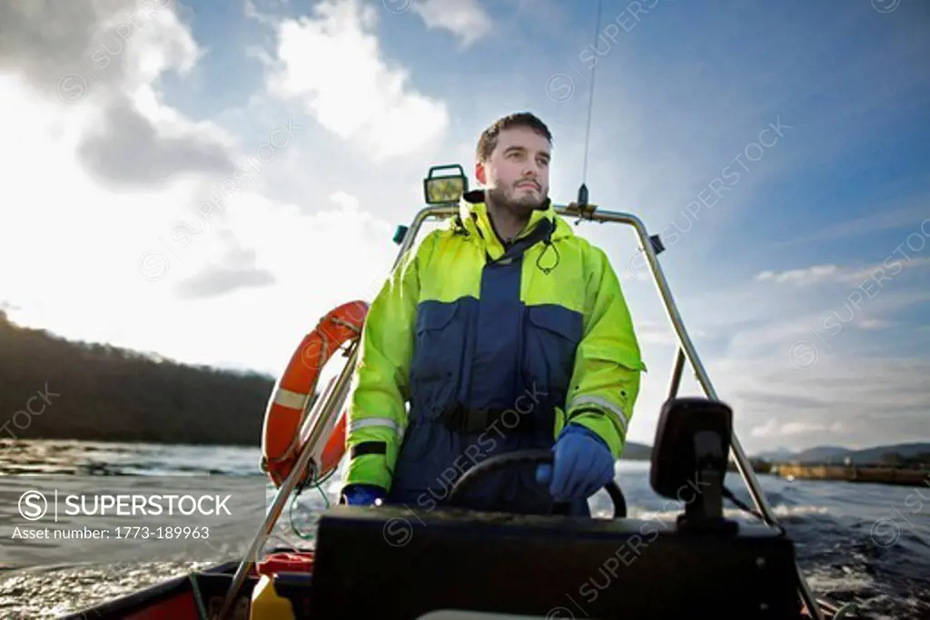 Worker driving boat in rural lake
