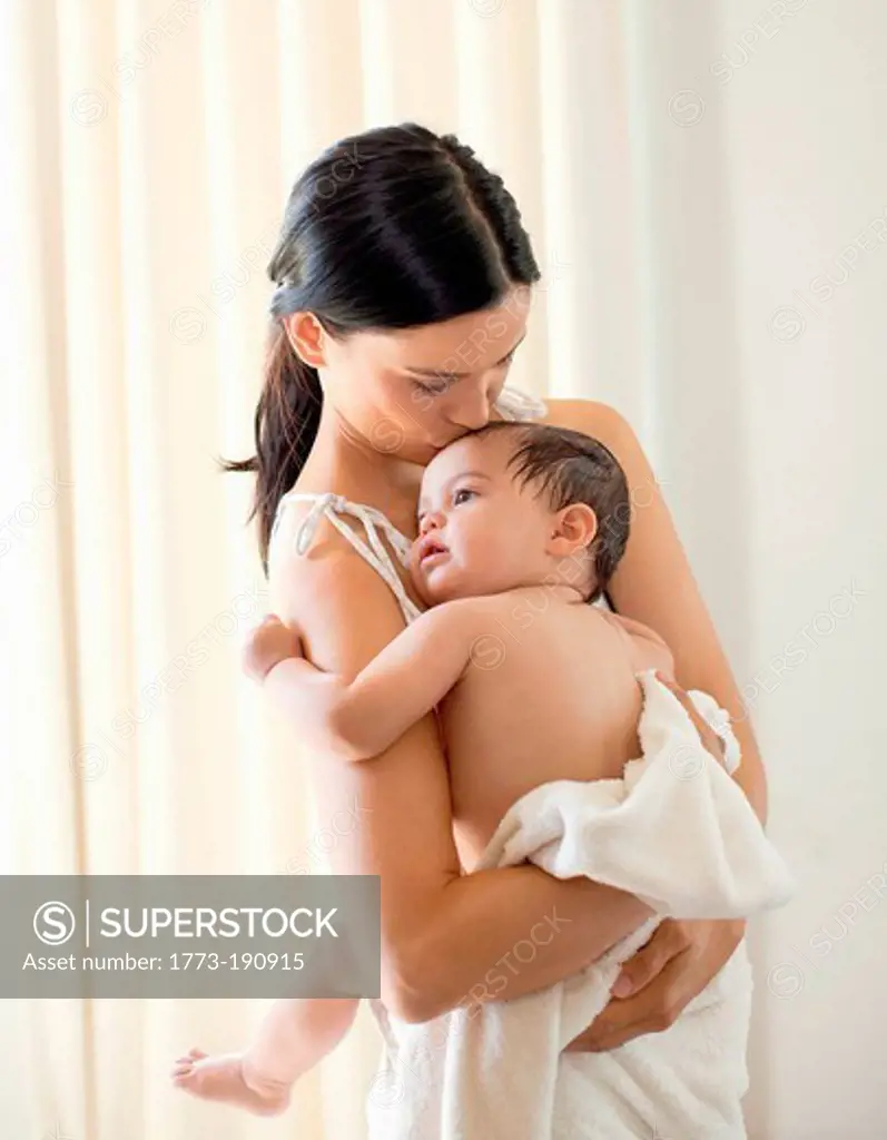 Mother kissing baby girl at bathtime