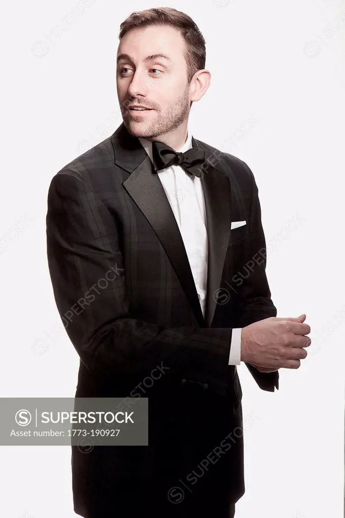 Man in tuxedo standing against white background
