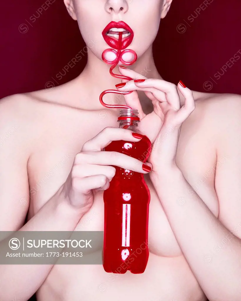 Woman drinking red soda with curly straw