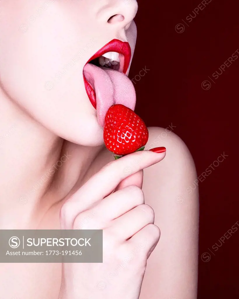 Woman licking strawberry