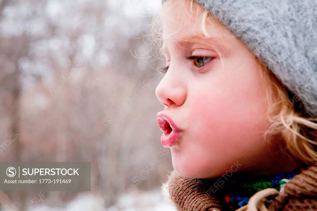 Little girl looking at her breath in the cold air