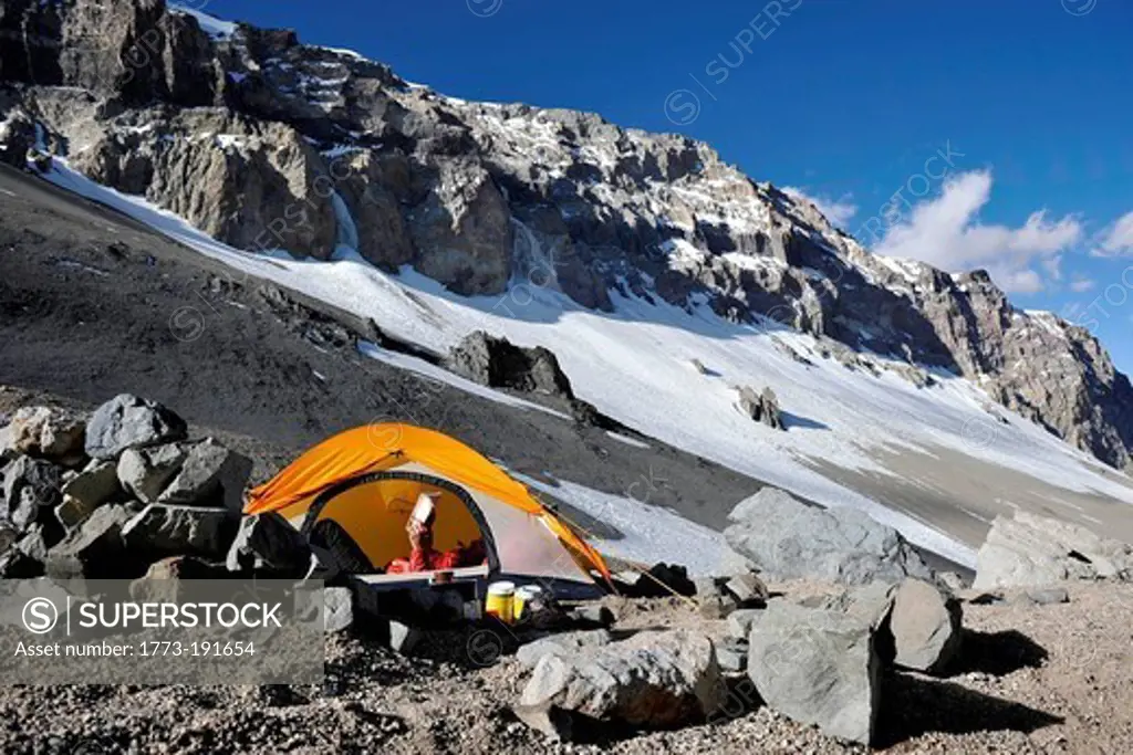 Woman reads in her tent at Camp One on Aconcagua in the Andes Mountains, Mendoza Province, Argentina