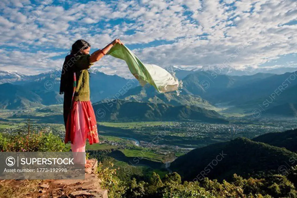 Nepalese woman holding scarf on cliff edge near Pokhara, Nepal