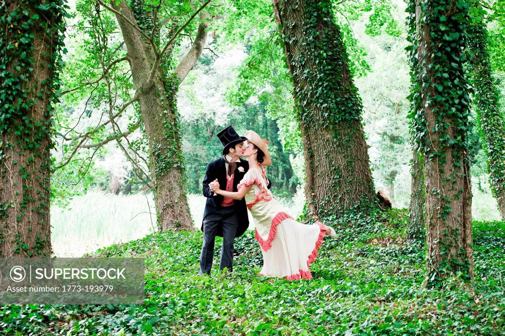 Bridal couple in 1920s style clothing, kissing in park