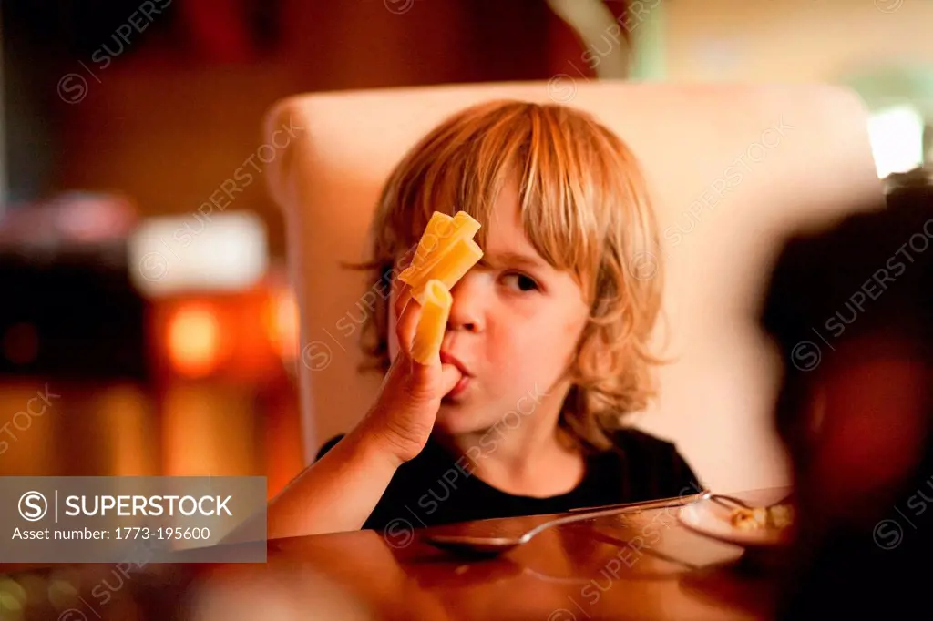 Boy eating pasta off fingers