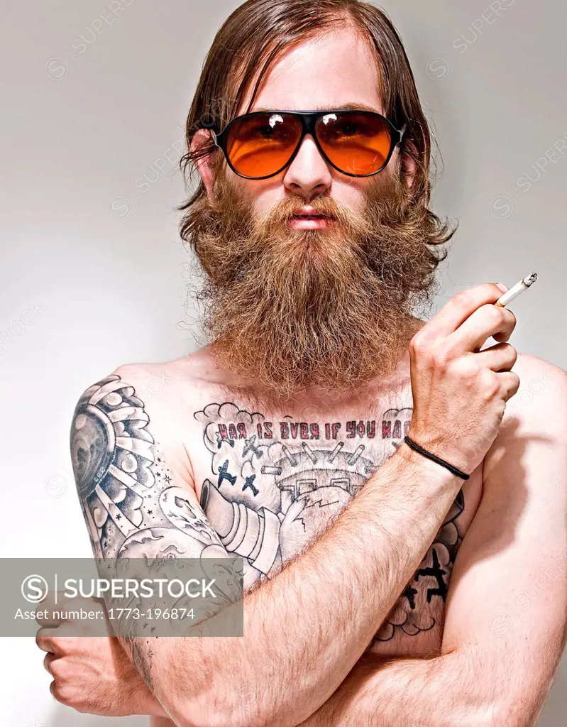Portrait of young man with tattoos smoking cigarette