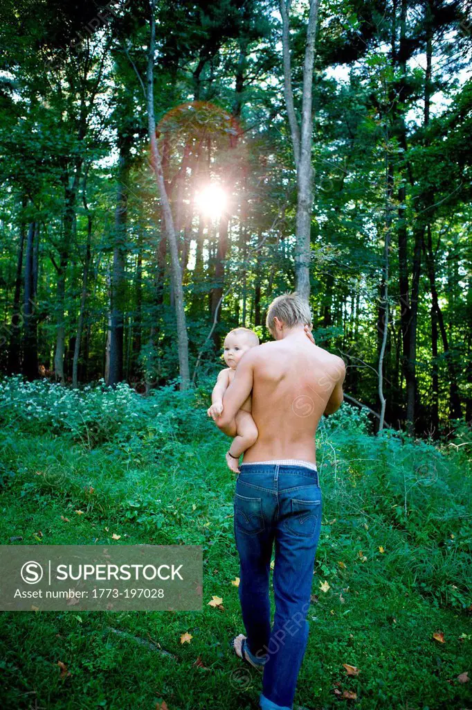 Father carrying baby girl in forest