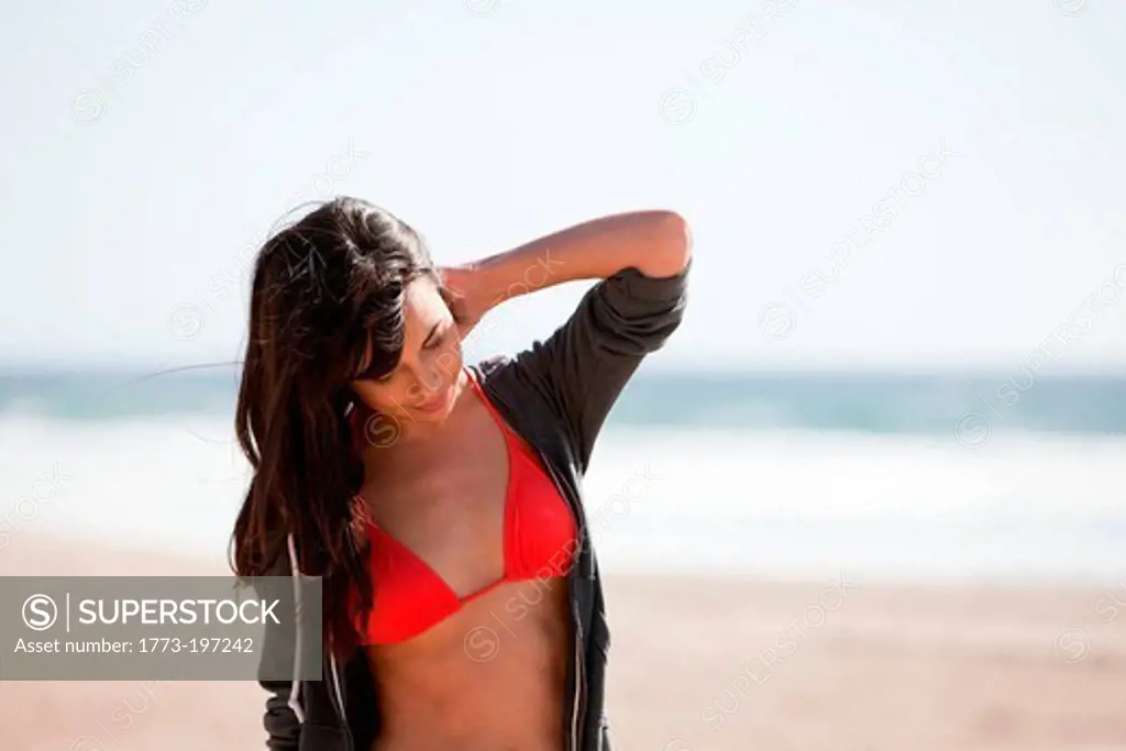 Young woman on beach with hand in hair