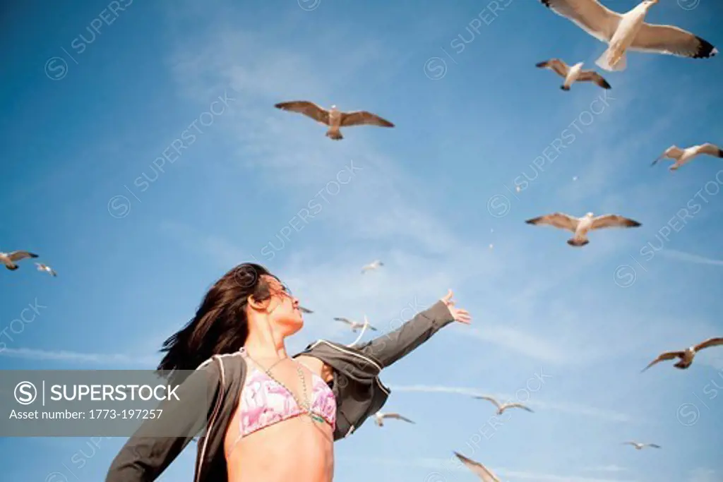 Young woman reaching towards gulls