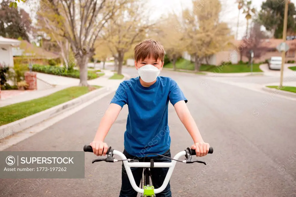 Boy on bicycle wearing dust mask