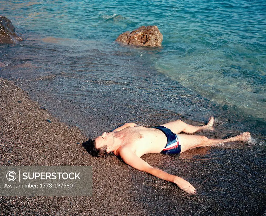 Man lying at water's edge, Crete, Greece