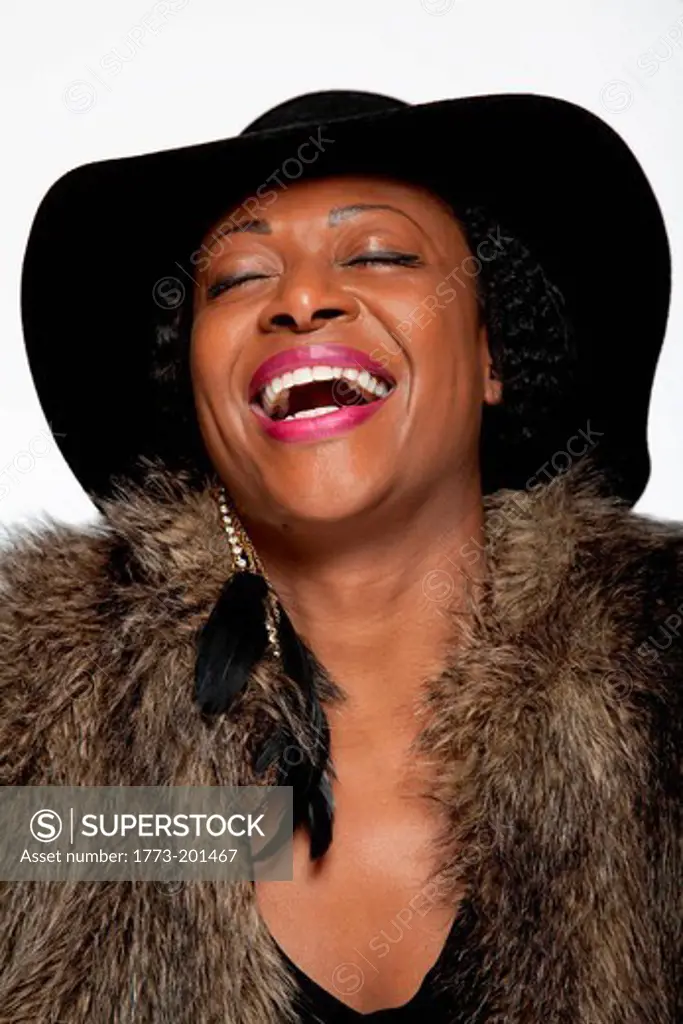 Portrait of woman wearing hat and fur coat, laughing
