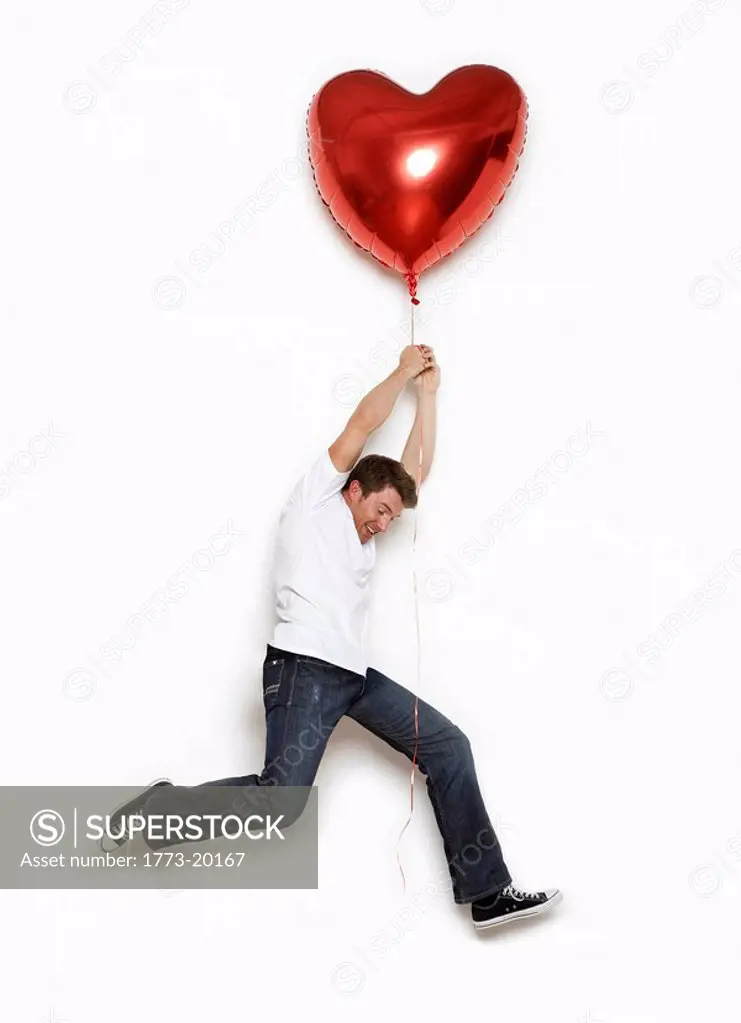 young man being lifted away by heart shaped helium balloon