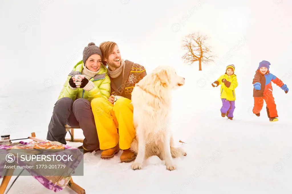 Parents with dog and children playing in background