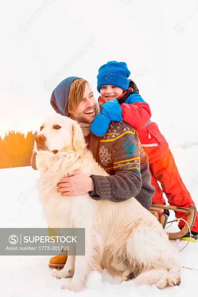 Father and son with dog in snow