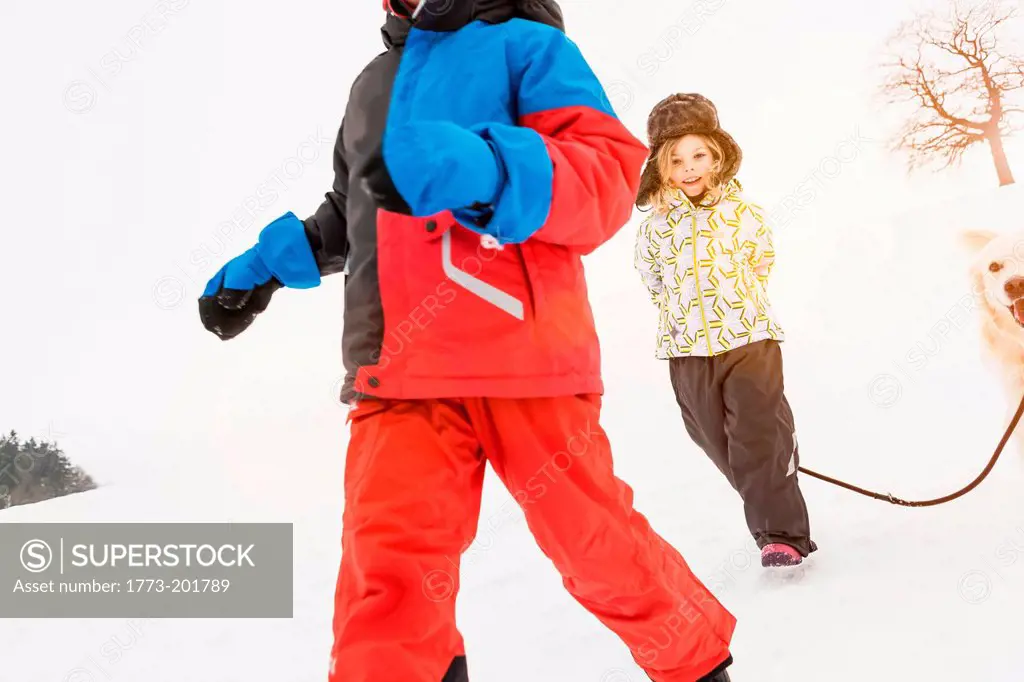 Girl with dog in snow with boy in foreground